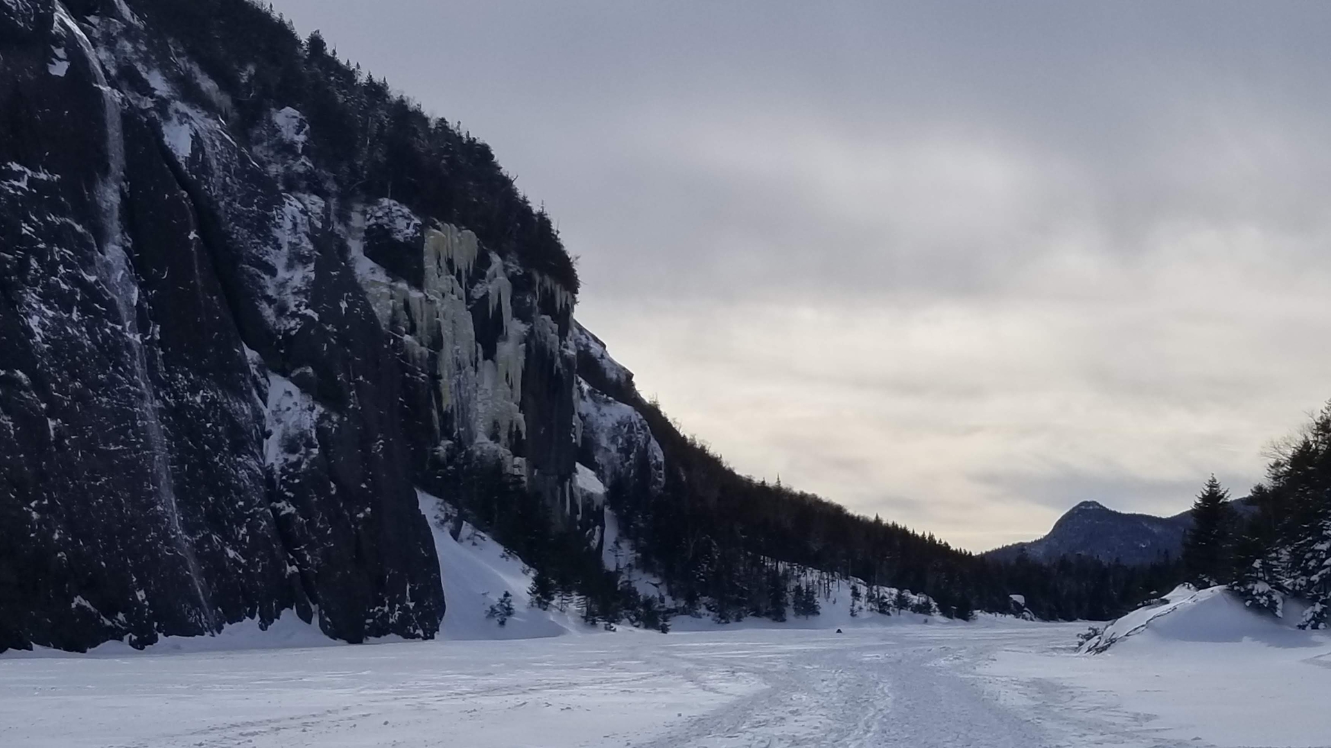 Avalanche lake in the winter, the surface and the cliffs clad in ice.
