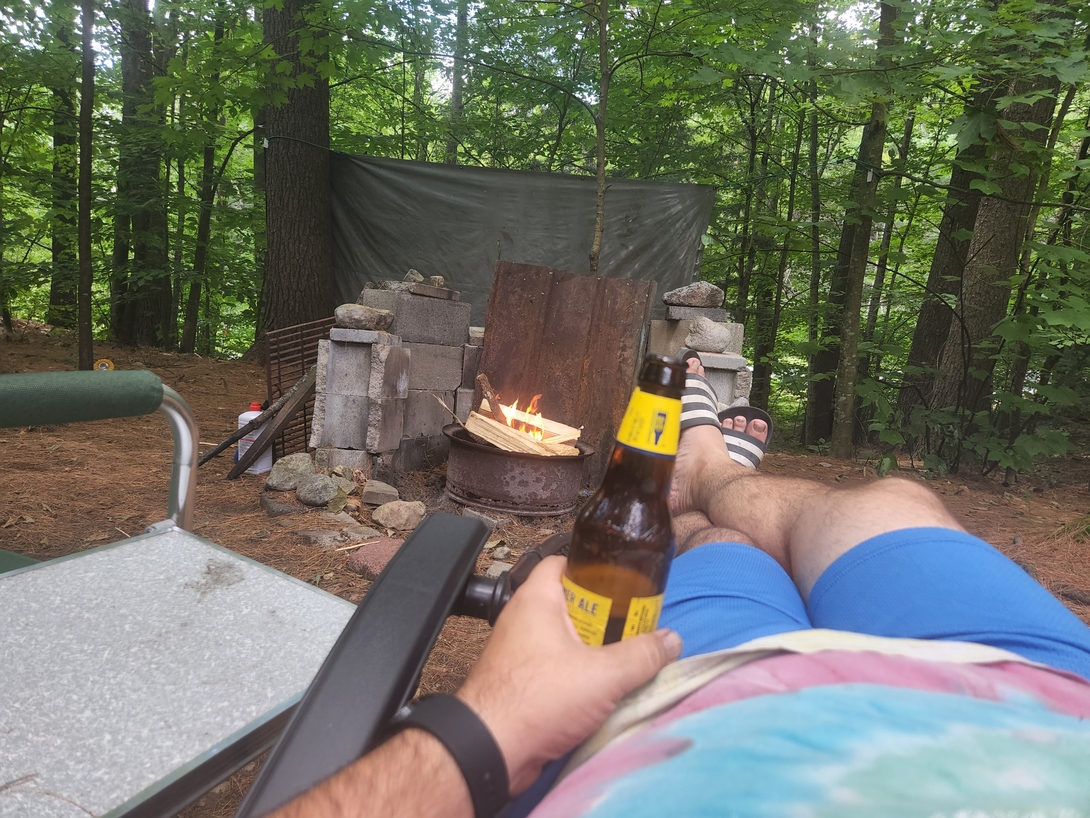 Adam relaxes beside the campfire with a beer after hiking Cascade and Porter mountains.